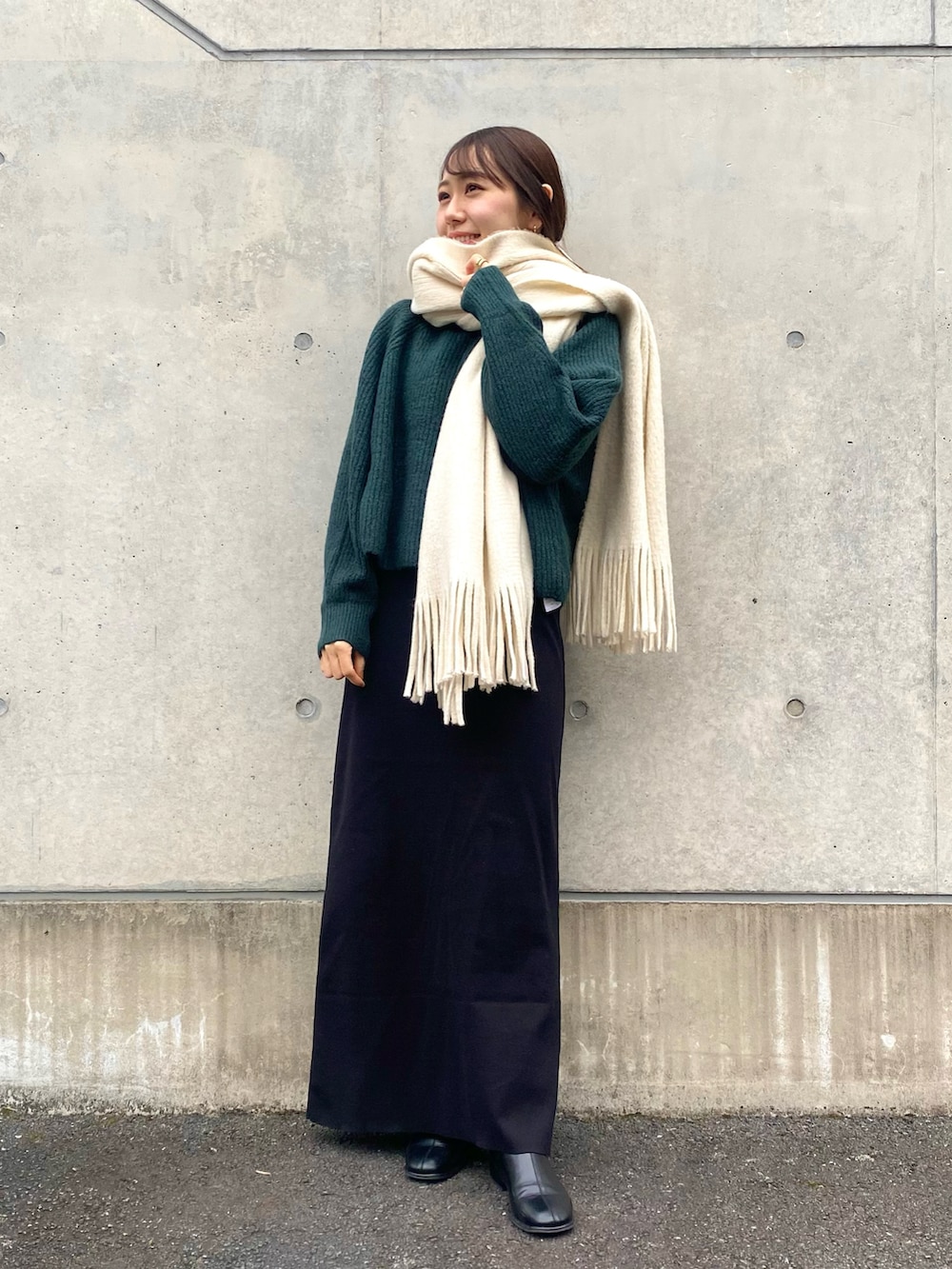 グリーン系のニット/セーター、ブラック系のその他シューズ、ホワイト系のマフラーを着用したレディースの冬コーディネートの4枚目の写真