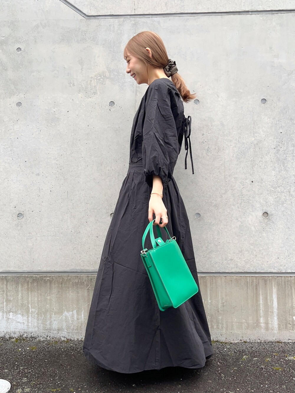 ブラック系のワンピース、グリーン系のトートバッグ、ブラック系のサンダルを着用したレディースの春コーディネートの3枚目の写真
