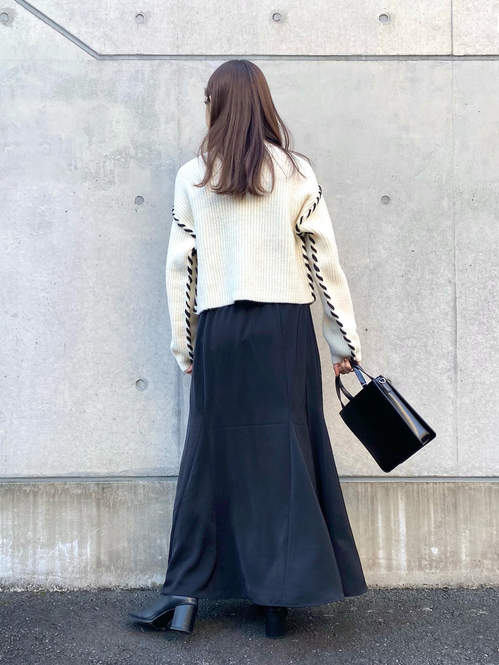 ホワイト系のニット/セーター、ブラック系のスカート、ブラック系のブーツを着用したレディースの秋コーディネートの3枚目の写真