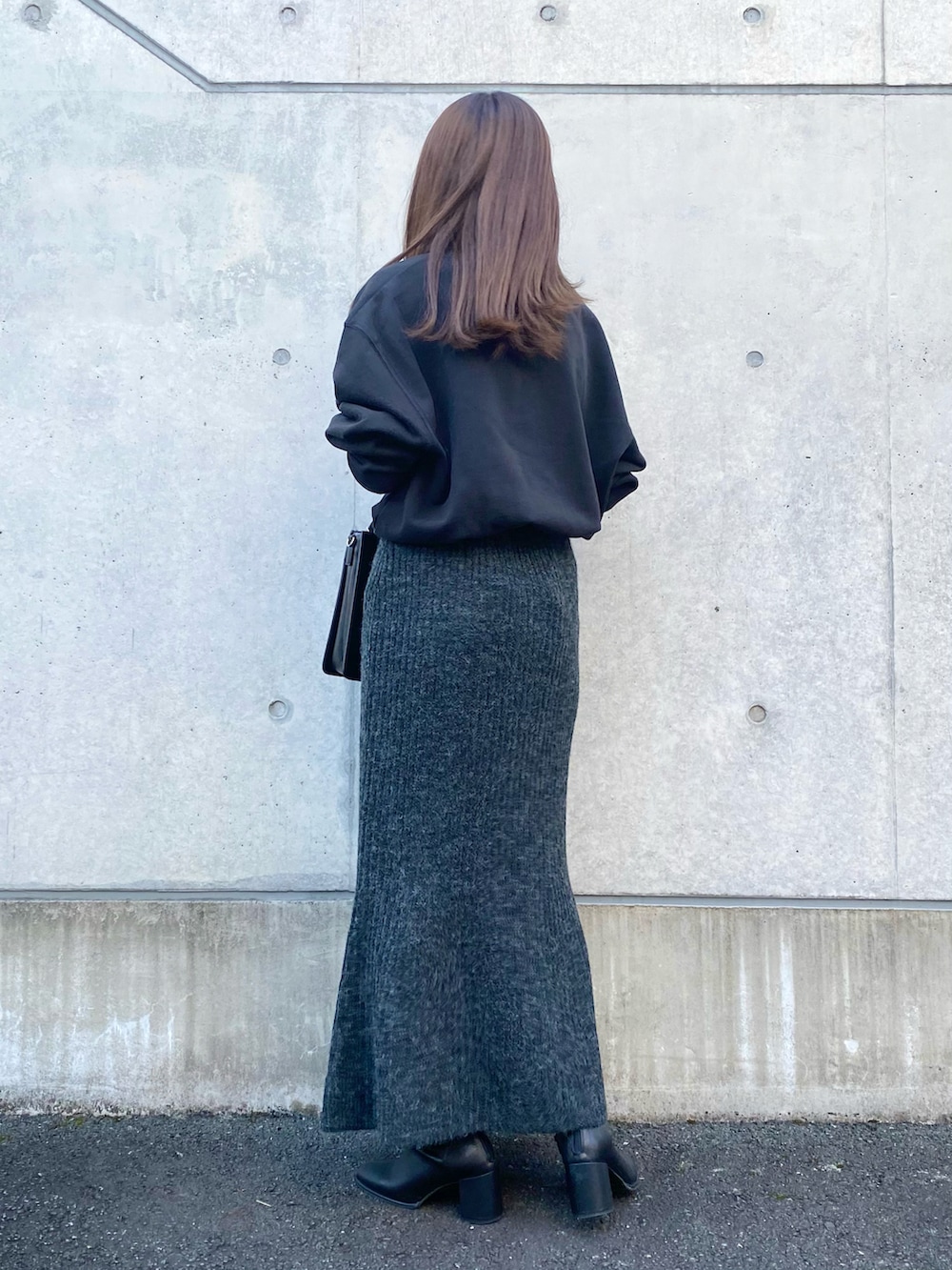 ブラック系のスカート、ブラック系のショルダーバッグ、ブラック系のブーツを着用したレディースの秋コーディネートの3枚目の写真