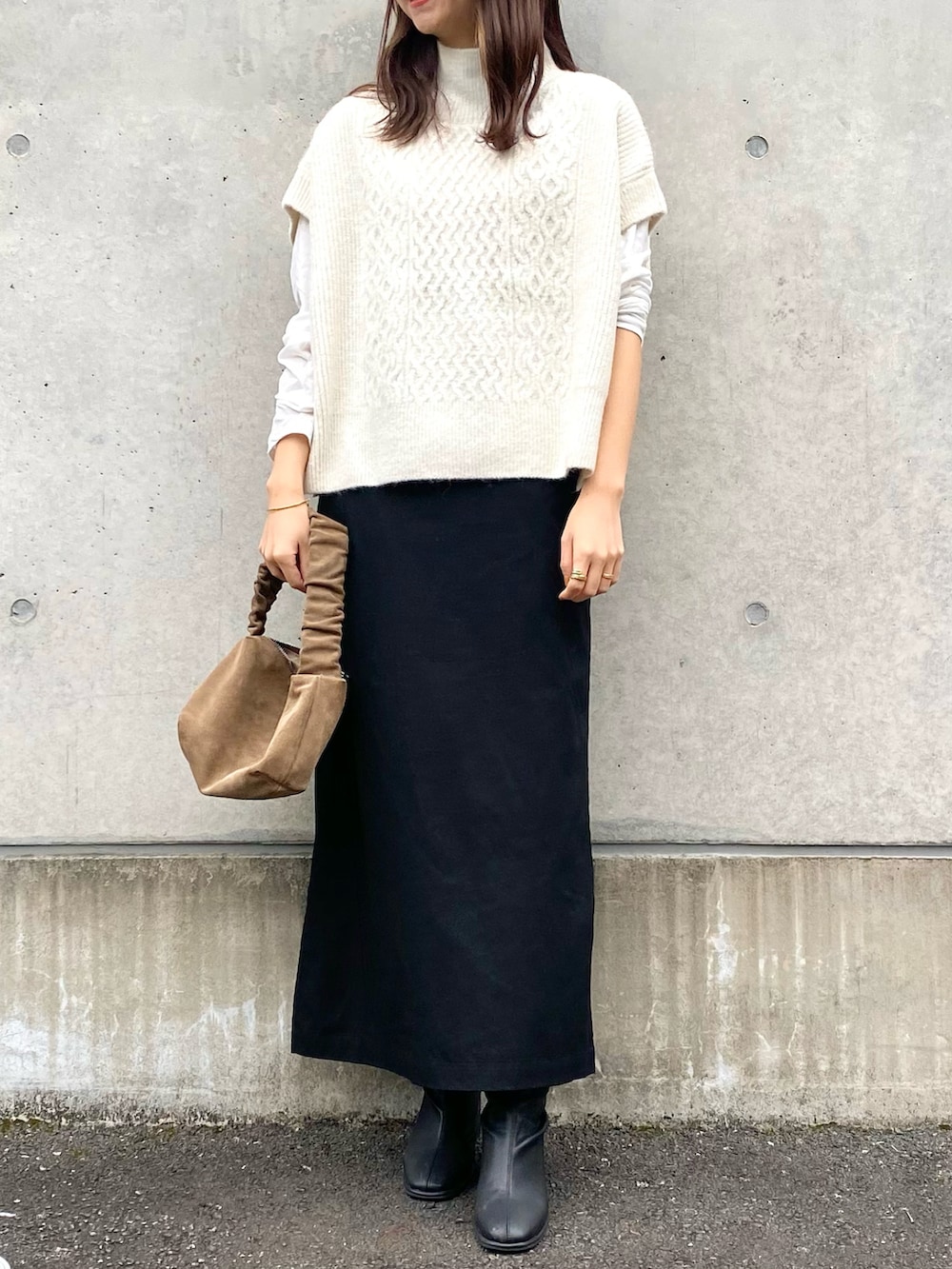 ホワイト系のベスト、ブラック系のスカート、ブラック系のブーツを着用したレディースの秋コーディネートの4枚目の写真