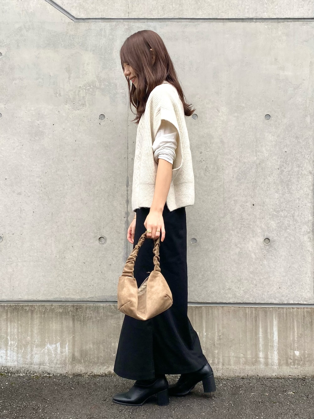 ホワイト系のベスト、ブラック系のスカート、ブラック系のブーツを着用したレディースの秋コーディネートの2枚目の写真
