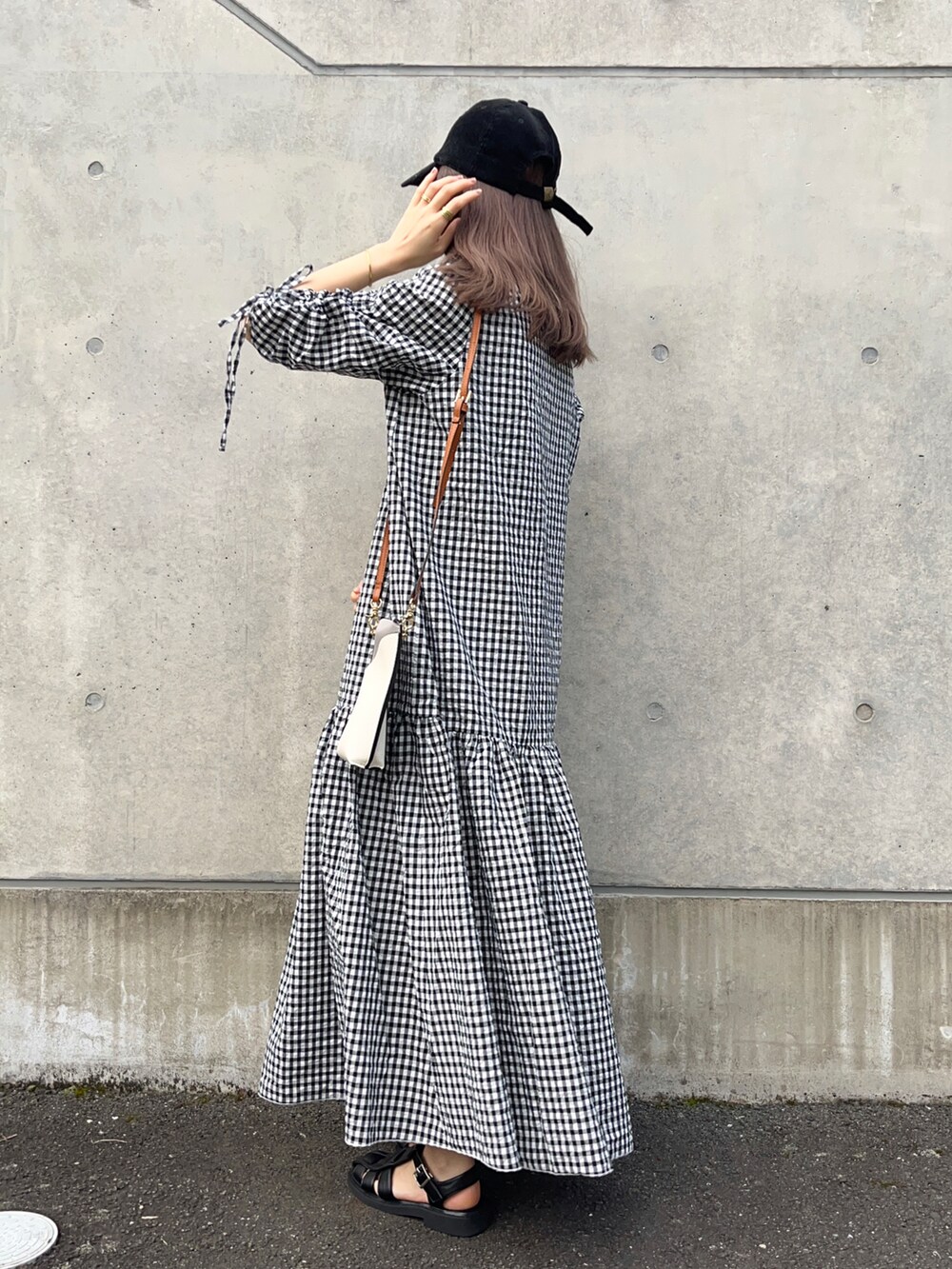 ブラック系のワンピース、ホワイト系のショルダーバッグ、ブラック系のサンダルを着用したレディースの春コーディネートの2枚目の写真