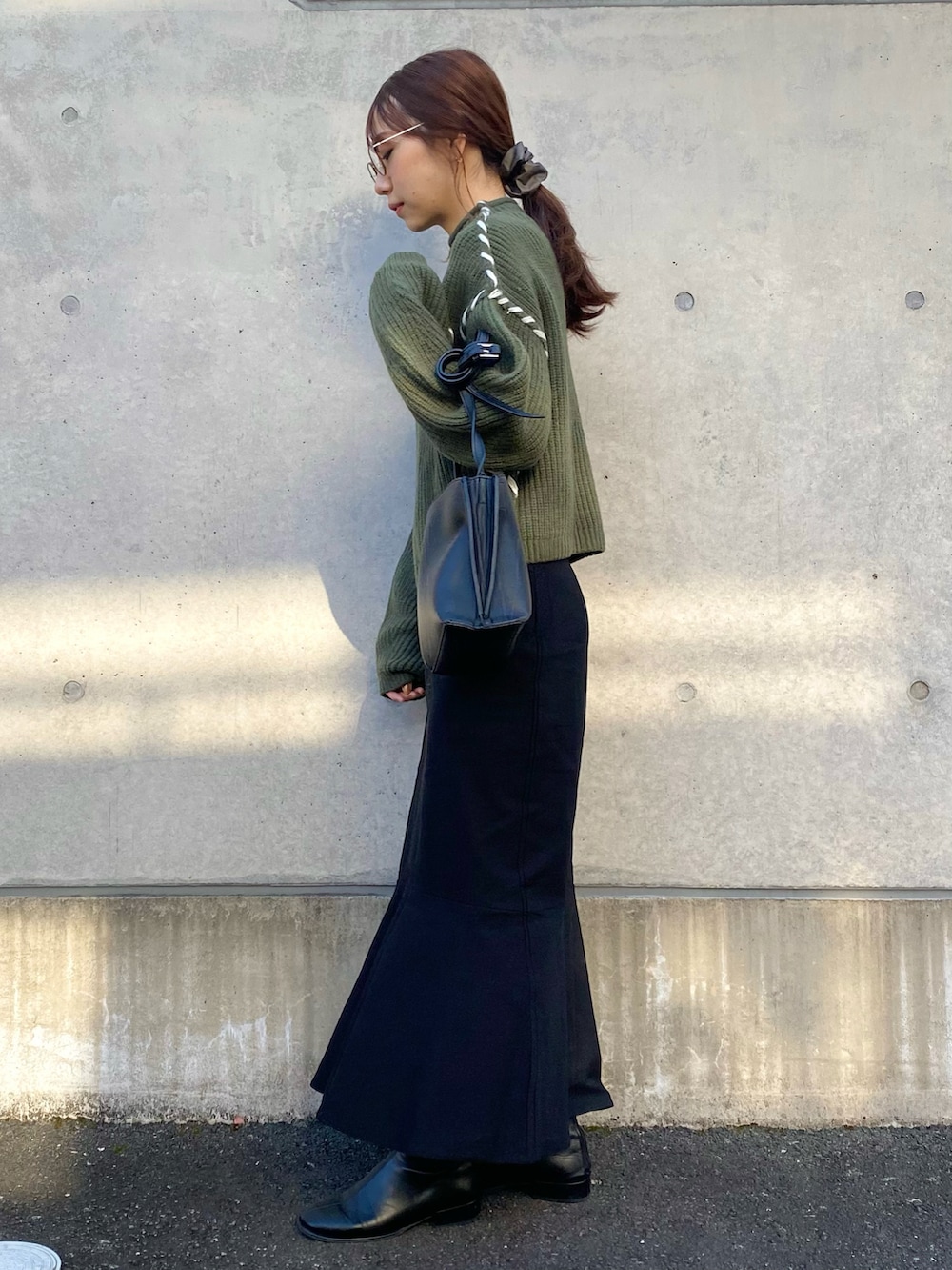 グリーン系のニット/セーター、ブラック系のスカート、ブラック系のその他シューズを着用したレディースの冬コーディネートの2枚目の写真