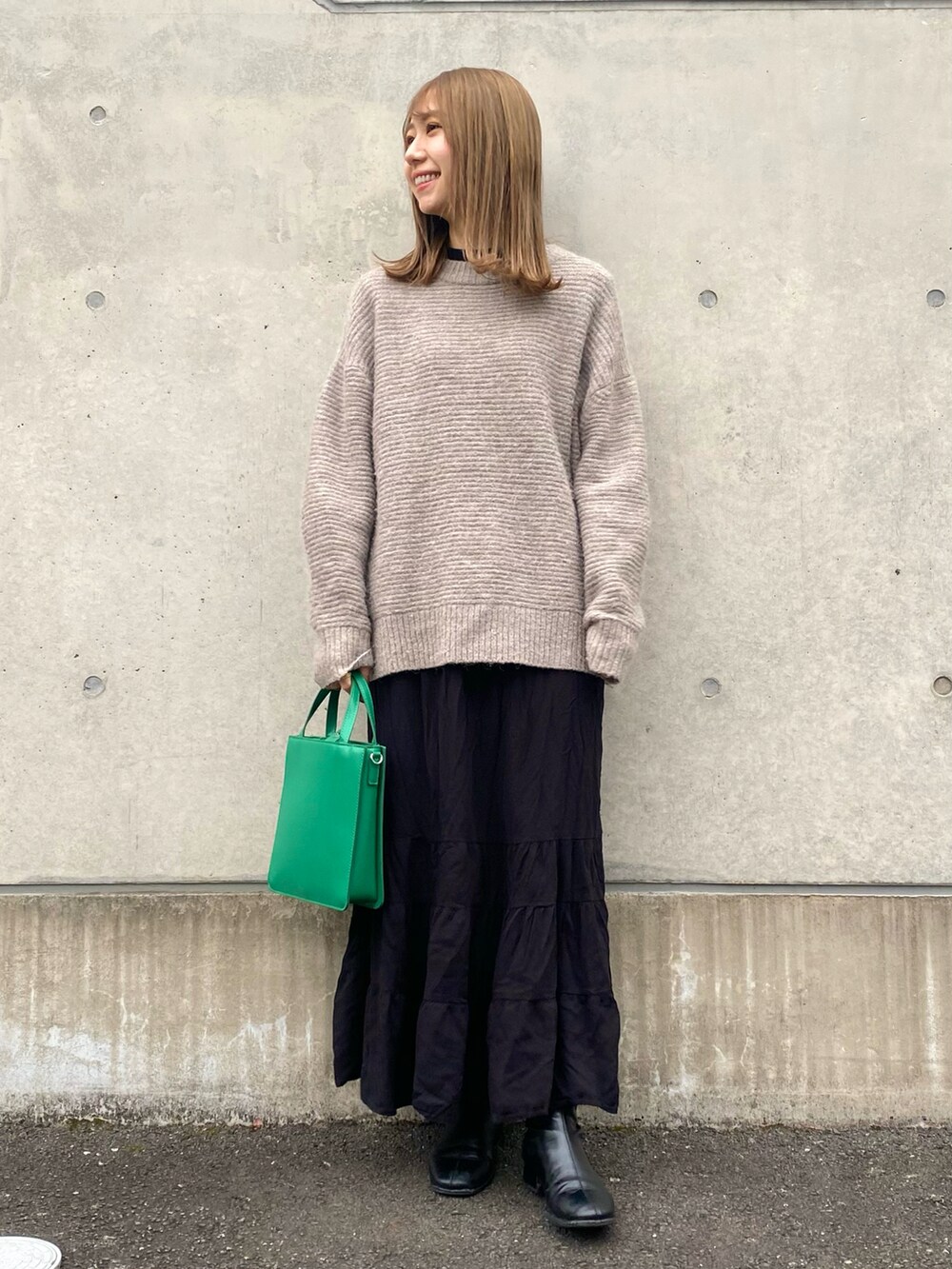 ブラック系のスカート、ホワイト系のTシャツ/カットソー、グレー系のニット/セーターを着用したレディースの冬コーディネートの2枚目の写真