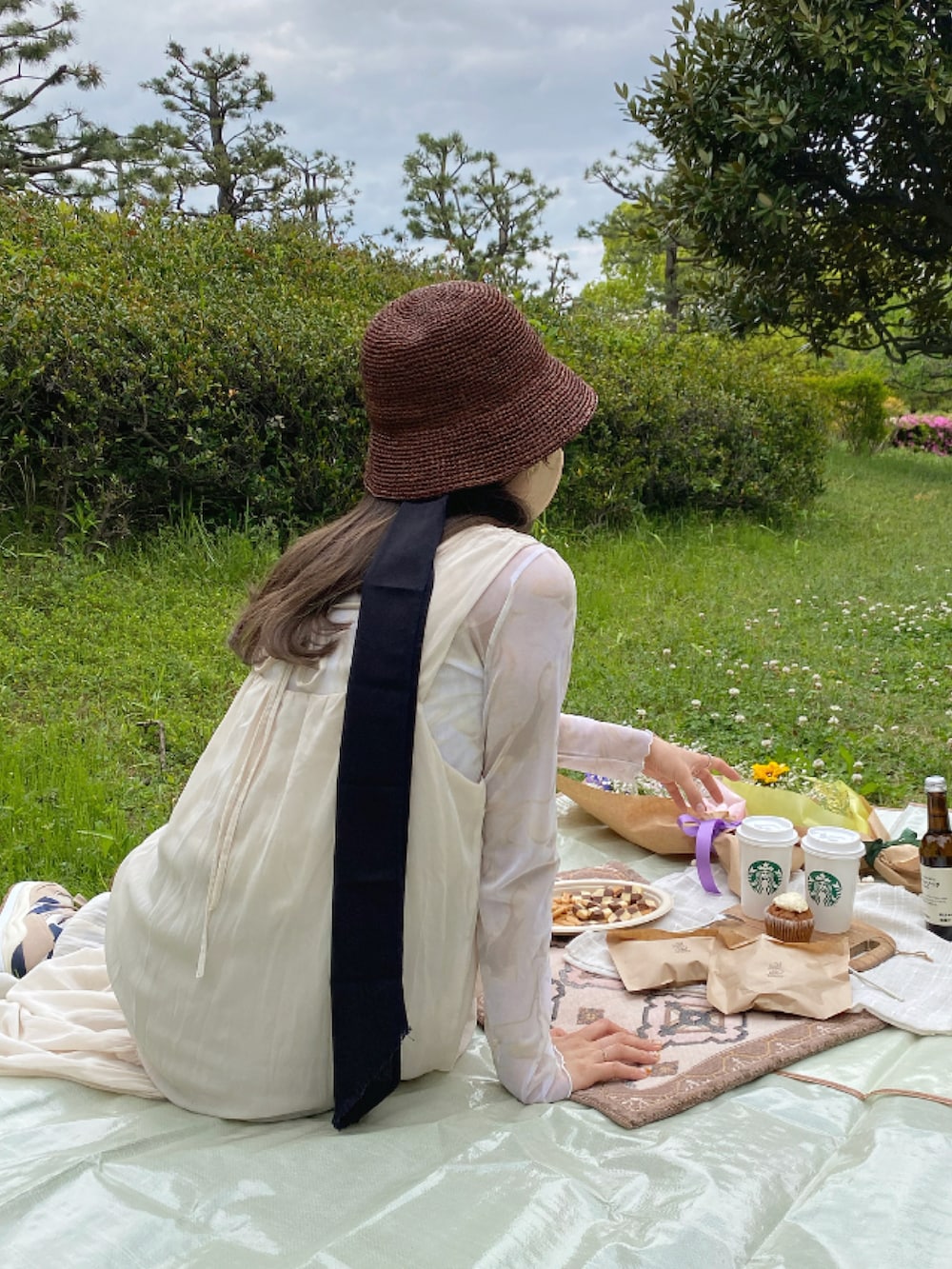 ホワイト系のミリタリージャケット、ホワイト系のワンピース、ブラウン系のハットを着用したレディースの春コーディネートの2枚目の写真