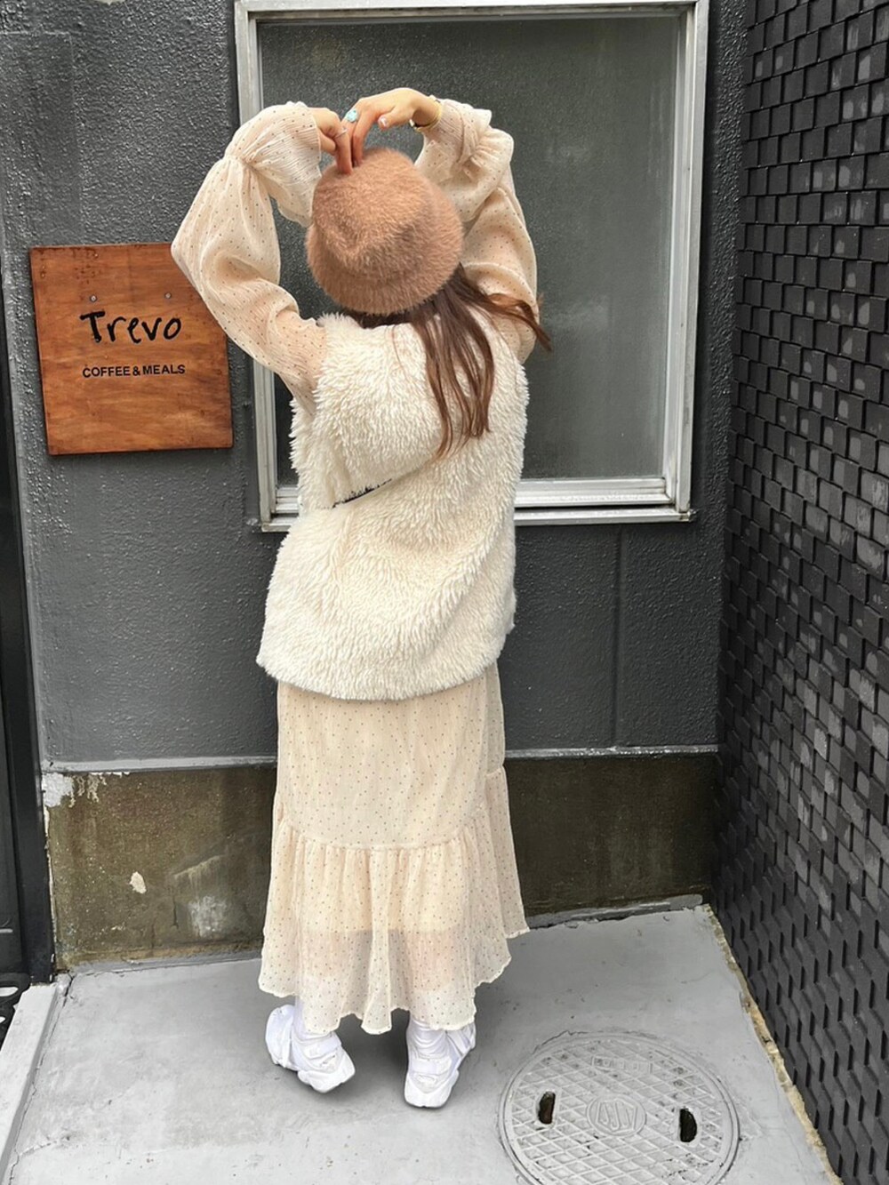 ホワイト系のベスト、ブラック系のショルダーバッグ、ホワイト系のスニーカーを着用したレディースの秋コーディネートの2枚目の写真