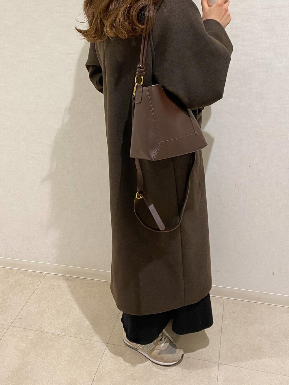 ブラウン系のニット/セーター、ブラウン系のスカート、ブラウン系のキャップを着用したレディースの冬コーディネートの2枚目の写真