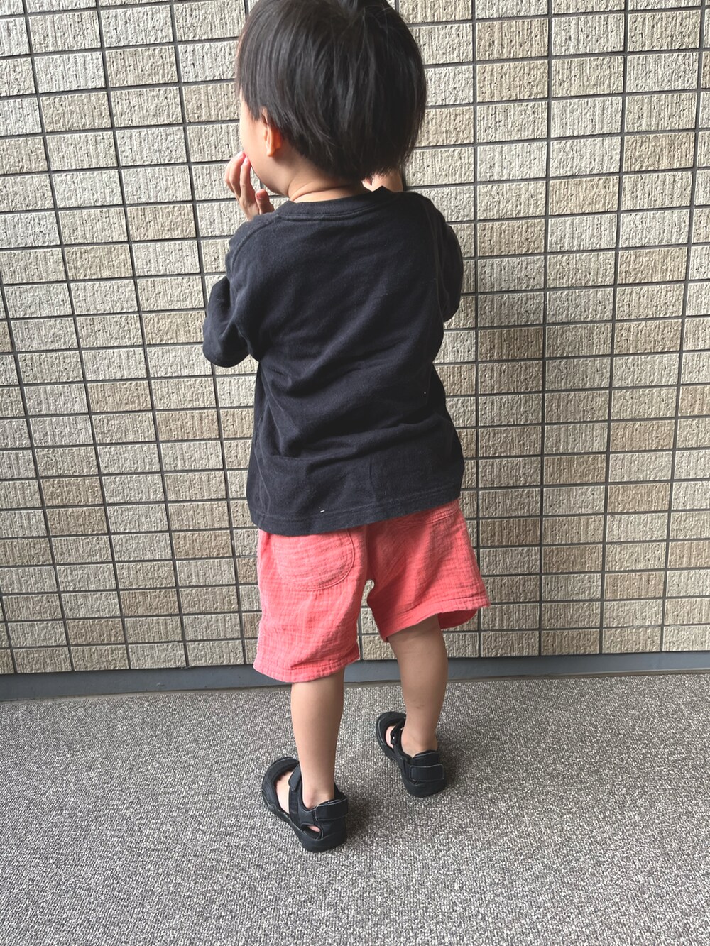 ブラック系のTシャツ/カットソー、レッド系のその他パンツ、ブラック系のサンダルを着用したキッズの秋コーディネートの2枚目の写真