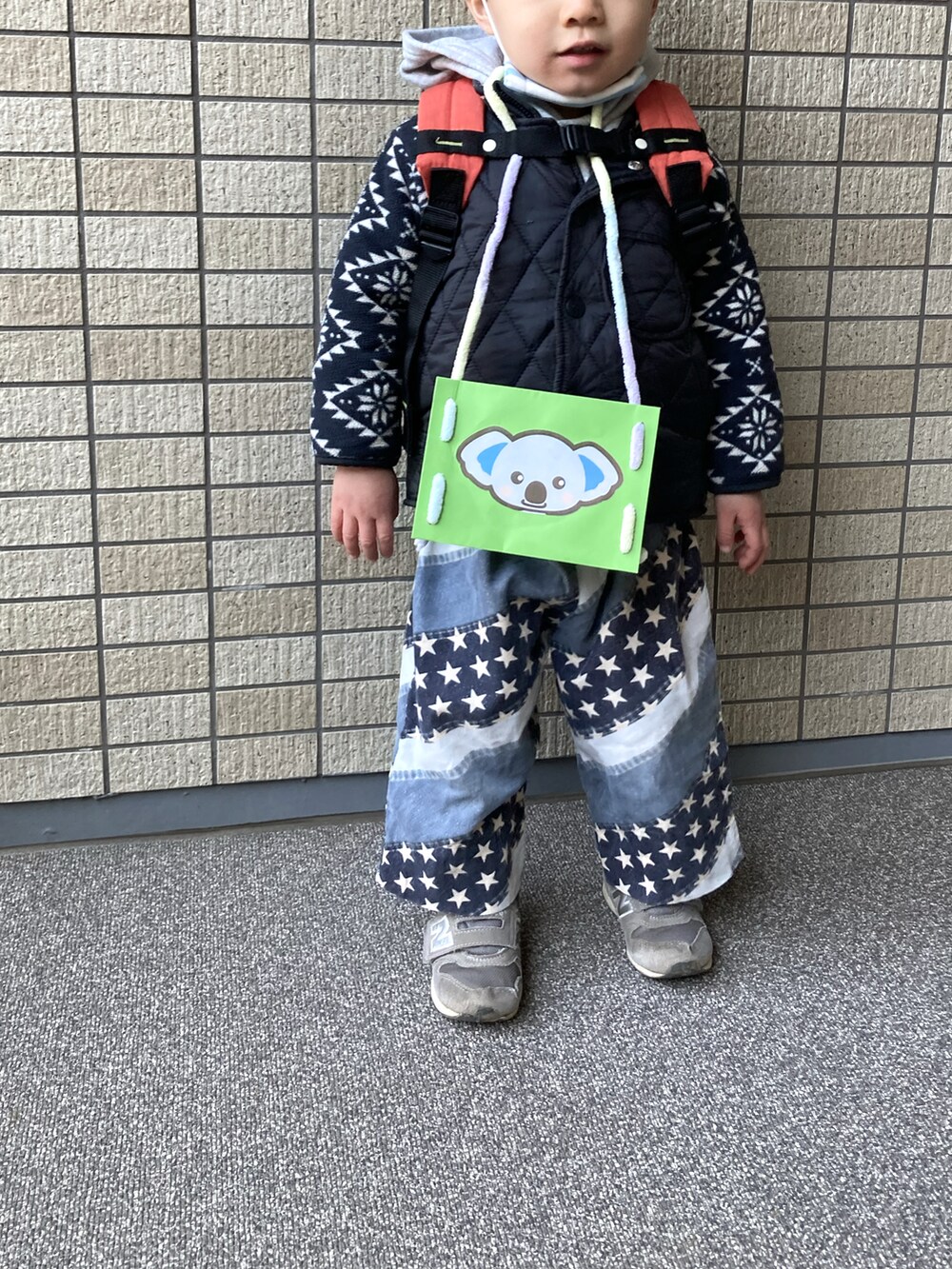 ブルー系のパンツ、グレー系のパーカー、ブラック系のダウンベストを着用したキッズの冬コーディネートの2枚目の写真