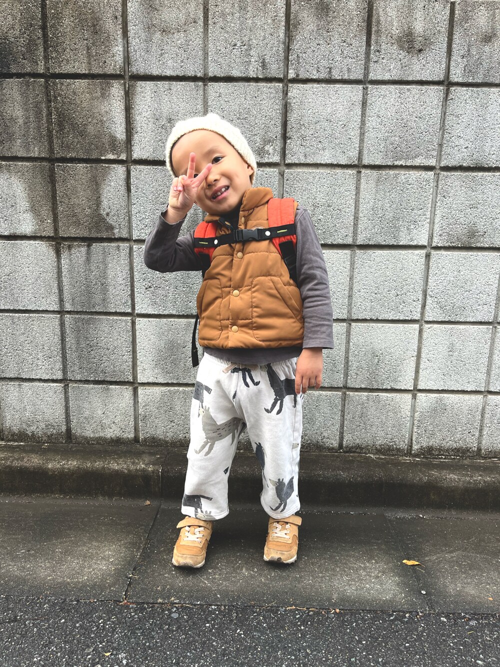 ブラウン系のダウンベスト、ブラック系のTシャツ/カットソー、ベージュ系のスウェットパンツを着用したキッズの秋コーディネートの2枚目の写真