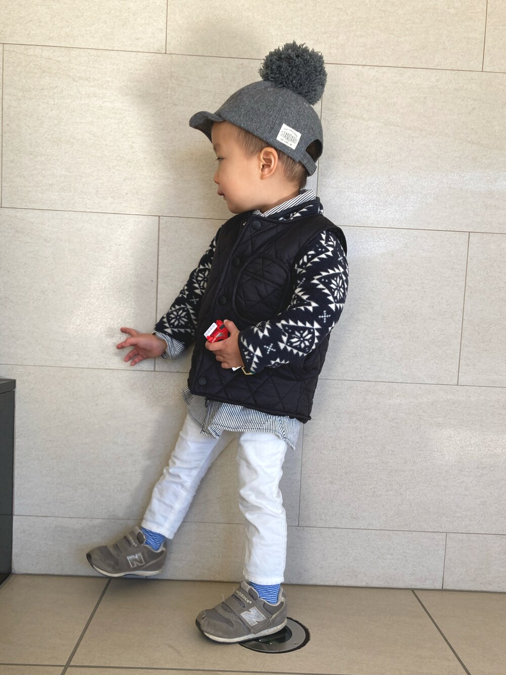 ブラック系のダウンベスト、ホワイト系のデニムパンツ、グレー系のスニーカーを着用したキッズの冬コーディネートの2枚目の写真