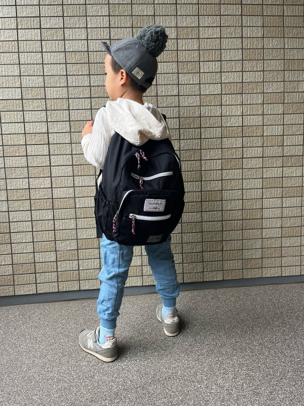 ブルー系のパンツ、ベージュ系のパーカー、ブラック系のバックパック/リュックを着用したキッズの秋コーディネートの2枚目の写真