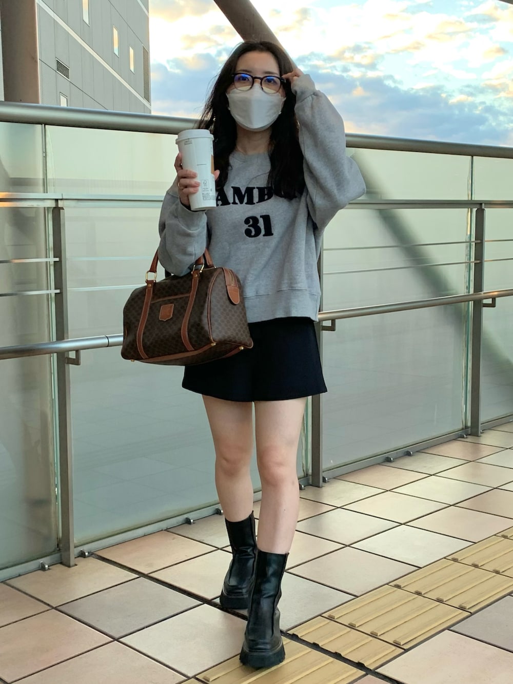 ブラウン系のボストンバッグ、ブラック系のパンツ、グレー系のスウェットを着用したレディースの秋コーディネートの3枚目の写真