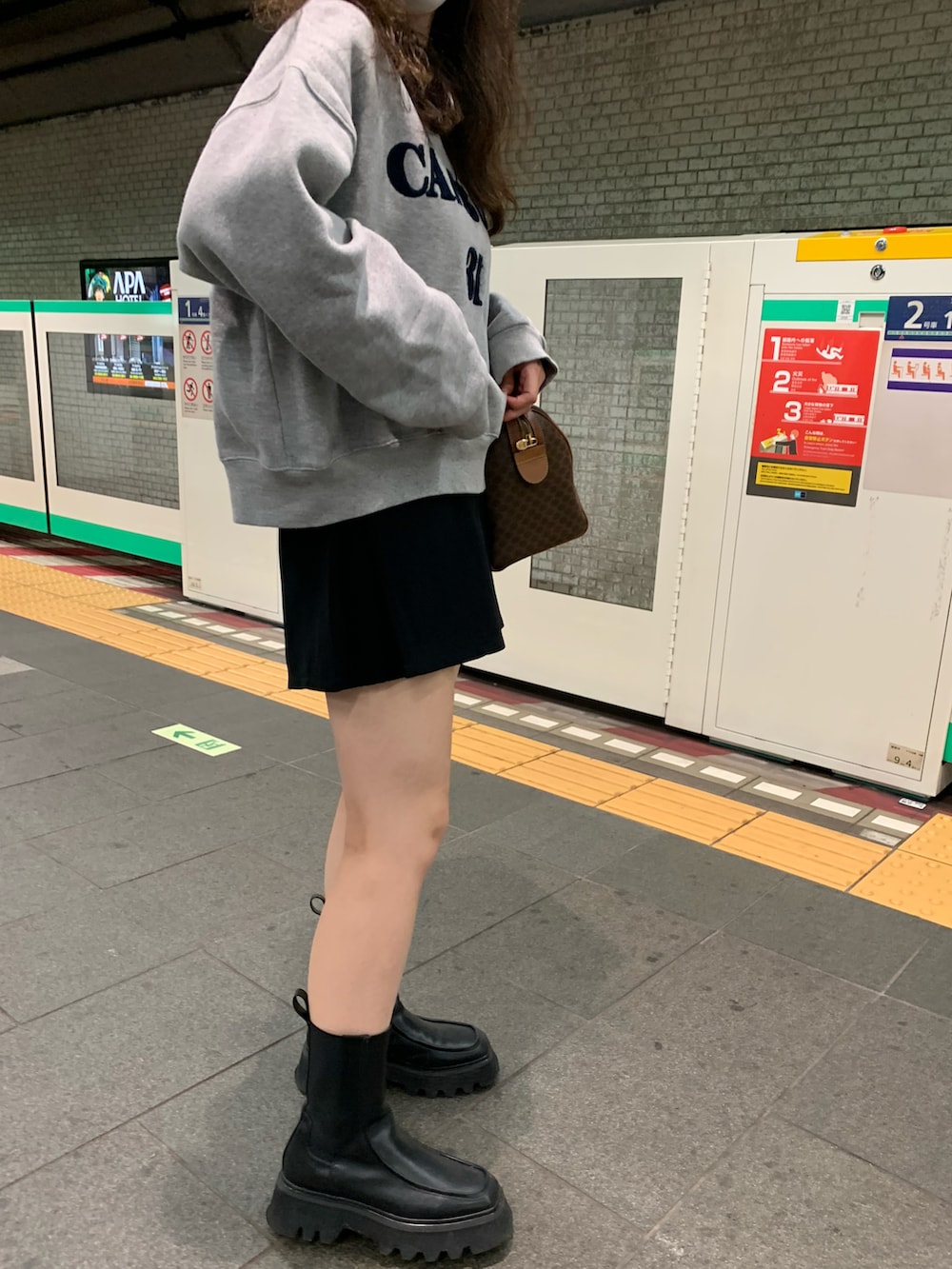 ブラウン系のボストンバッグ、ブラック系のパンツ、グレー系のスウェットを着用したレディースの秋コーディネートの2枚目の写真