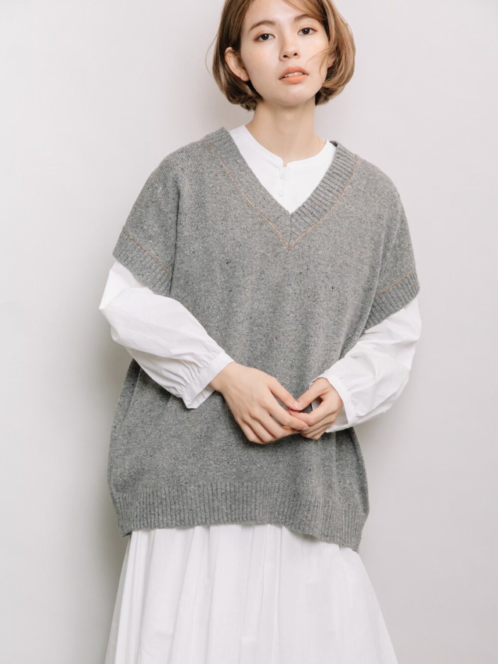 グレー系のベスト、ホワイト系のシャツ/ブラウス、ホワイト系のスカートを着用したレディースの春コーディネートの4枚目の写真