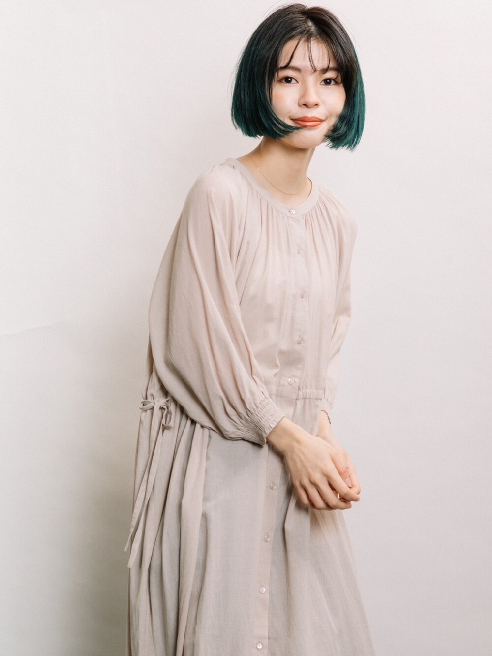 ベージュ系のワンピース、ブルー系のデニムパンツ、グレー系のスニーカーを着用したレディースの春コーディネートの3枚目の写真