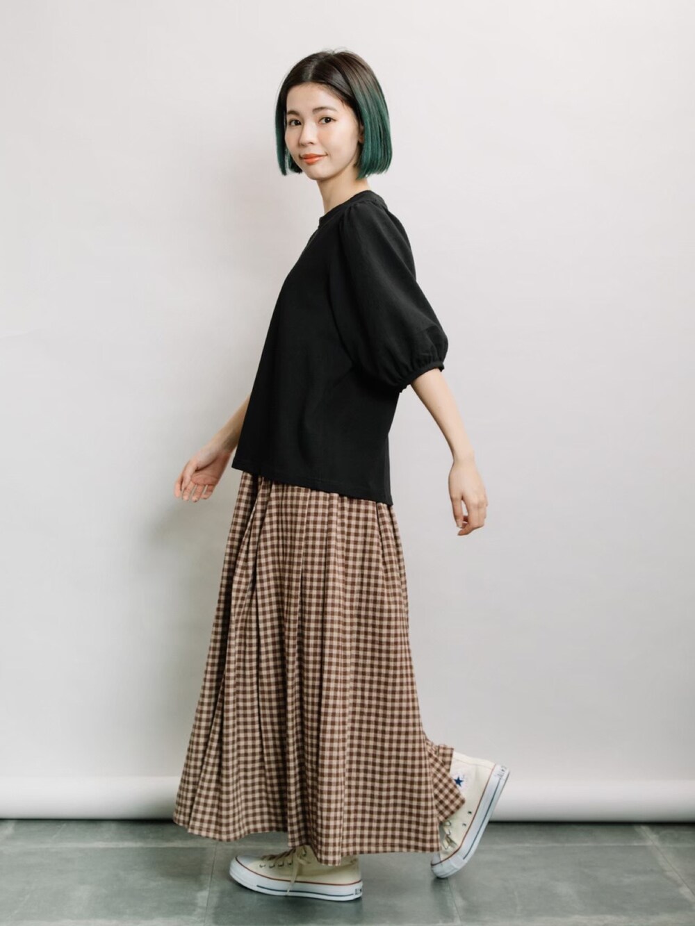 ブラック系のTシャツ/カットソー、ブラウン系のスカート、ホワイト系のスニーカーを着用したレディースの春コーディネートの2枚目の写真