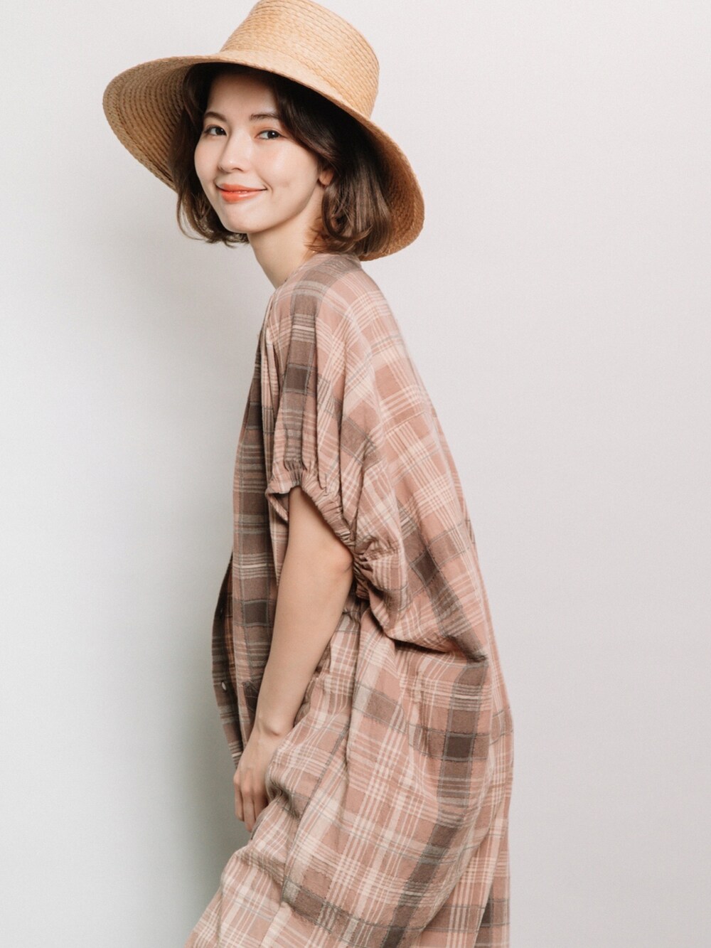 ベージュ系のシャツワンピース、ブルー系のデニムパンツ、ベージュ系のハットを着用したレディースの夏コーディネートの2枚目の写真