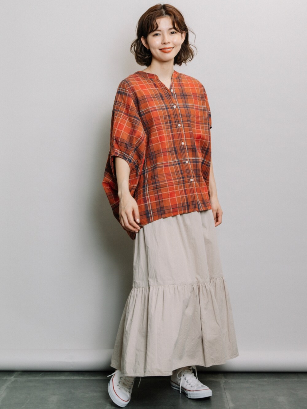 オレンジ系のシャツ/ブラウス、グレー系のスカート、ホワイト系のスニーカーを着用したレディースの夏コーディネートの2枚目の写真