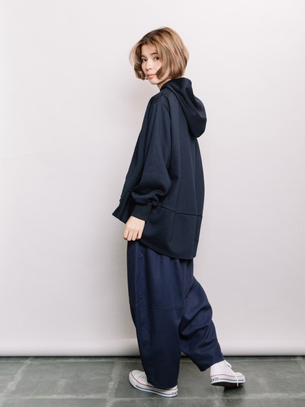 ブルー系のパーカー、ブルー系のデニムパンツ、ホワイト系のスニーカーを着用したレディースの冬コーディネートの3枚目の写真