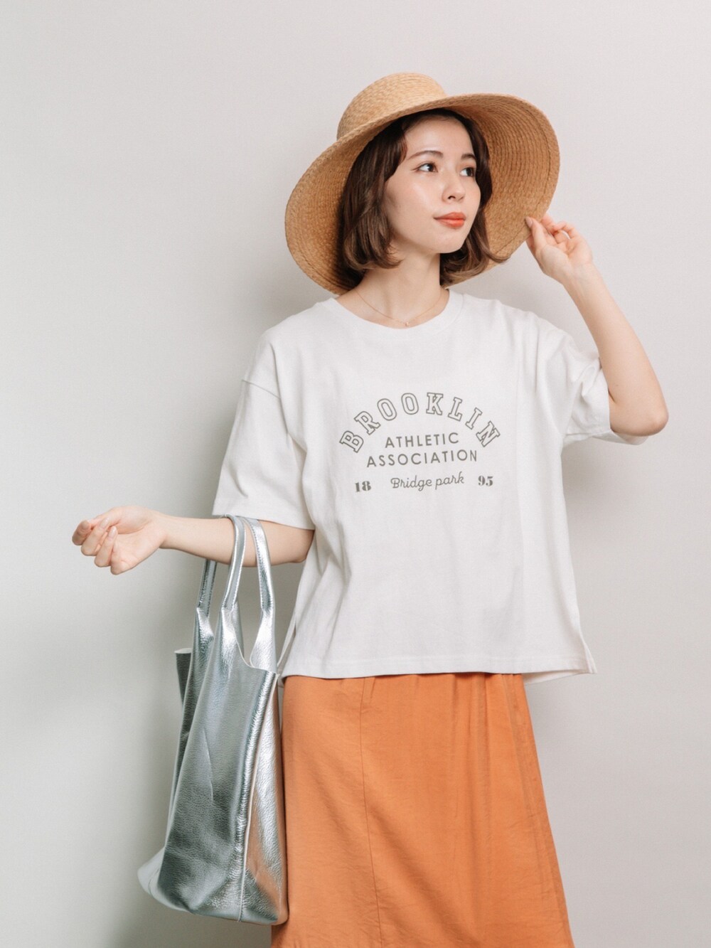ホワイト系のTシャツ/カットソー、オレンジ系のスカート、ベージュ系のハットを着用したレディースの夏コーディネートの3枚目の写真