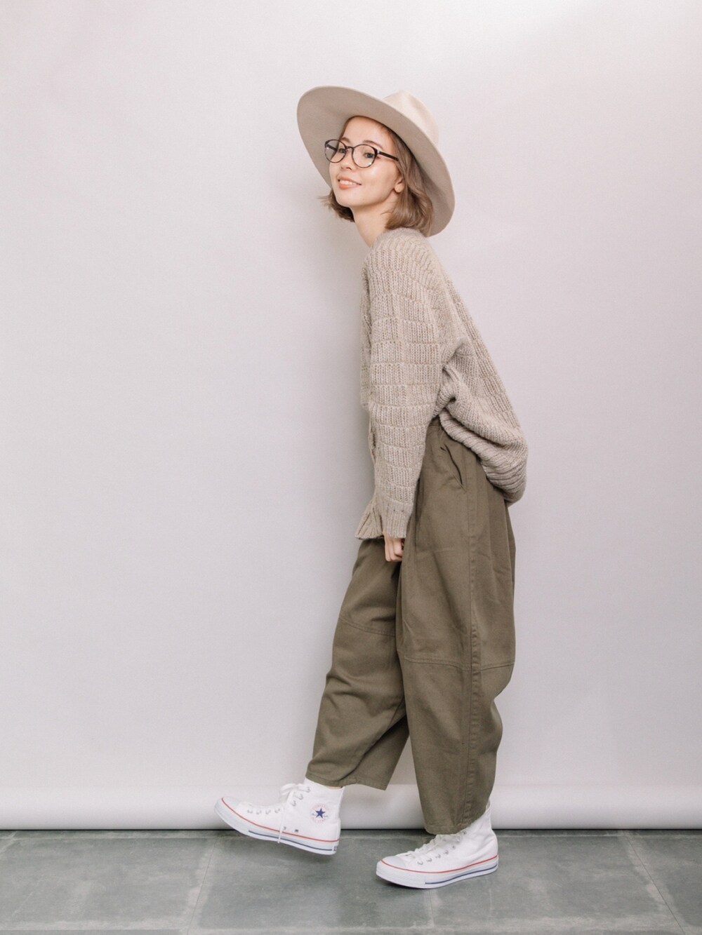 ベージュ系のニット/セーター、グリーン系のその他パンツ、ホワイト系のスニーカーを着用したレディースの秋コーディネートの2枚目の写真