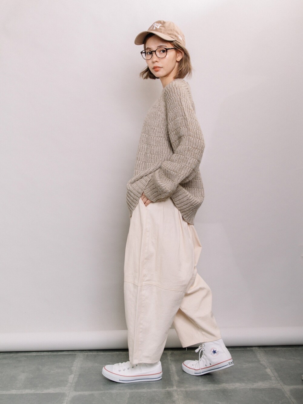 ベージュ系のニット/セーター、ホワイト系のその他パンツ、ホワイト系のスニーカーを着用したレディースの秋コーディネートの2枚目の写真
