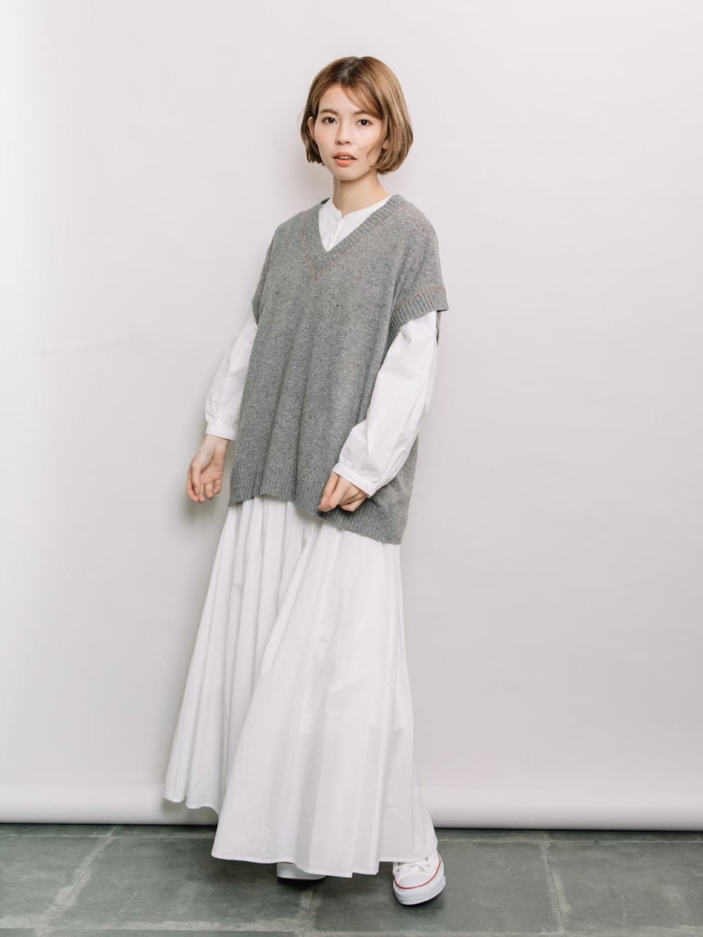 グレー系のベスト、ホワイト系のシャツ/ブラウス、ホワイト系のスカートを着用したレディースの春コーディネートの2枚目の写真