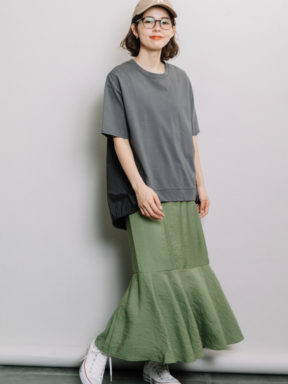 グレー系のTシャツ/カットソー、グリーン系のスカート、ホワイト系のスニーカーを着用したレディースの春コーディネートの2枚目の写真