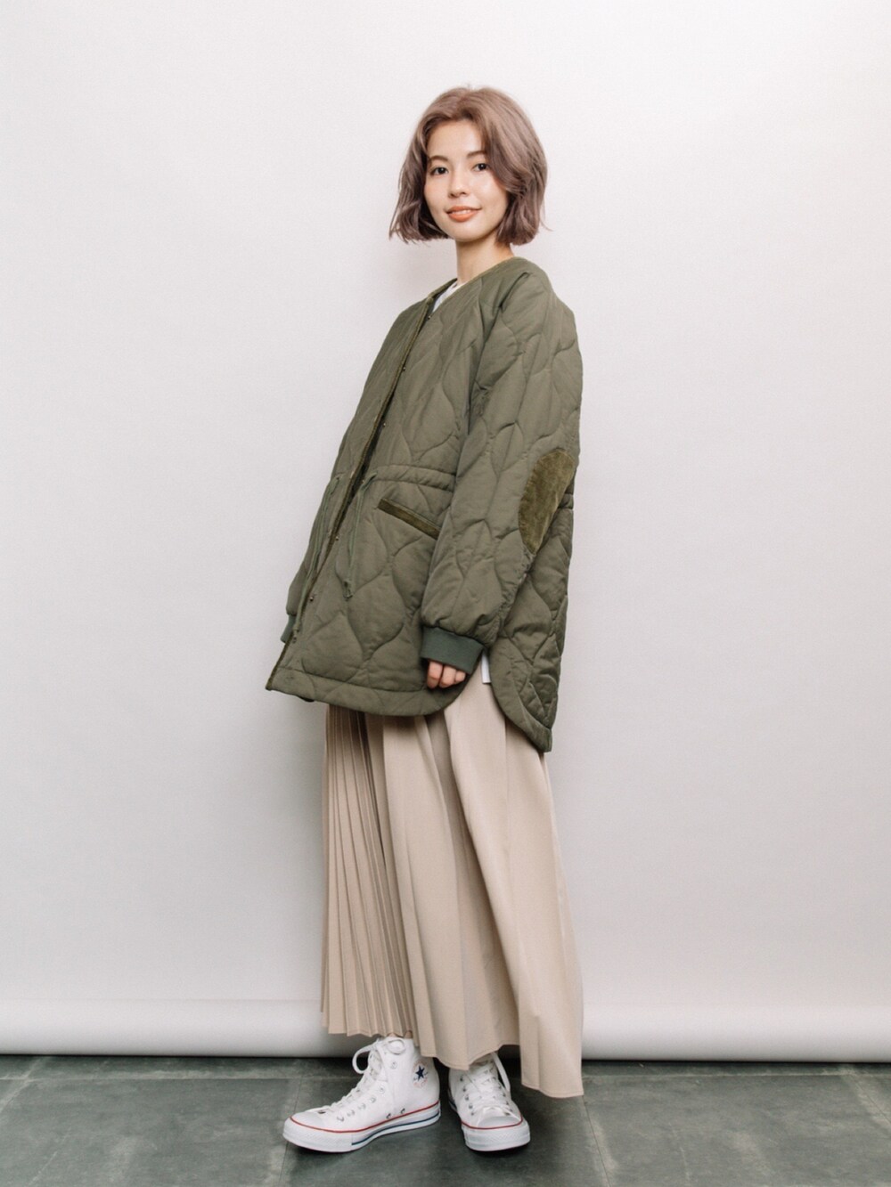 グリーン系のその他アウター、ベージュ系のスカート、ホワイト系のスニーカーを着用したレディースの冬コーディネートの2枚目の写真