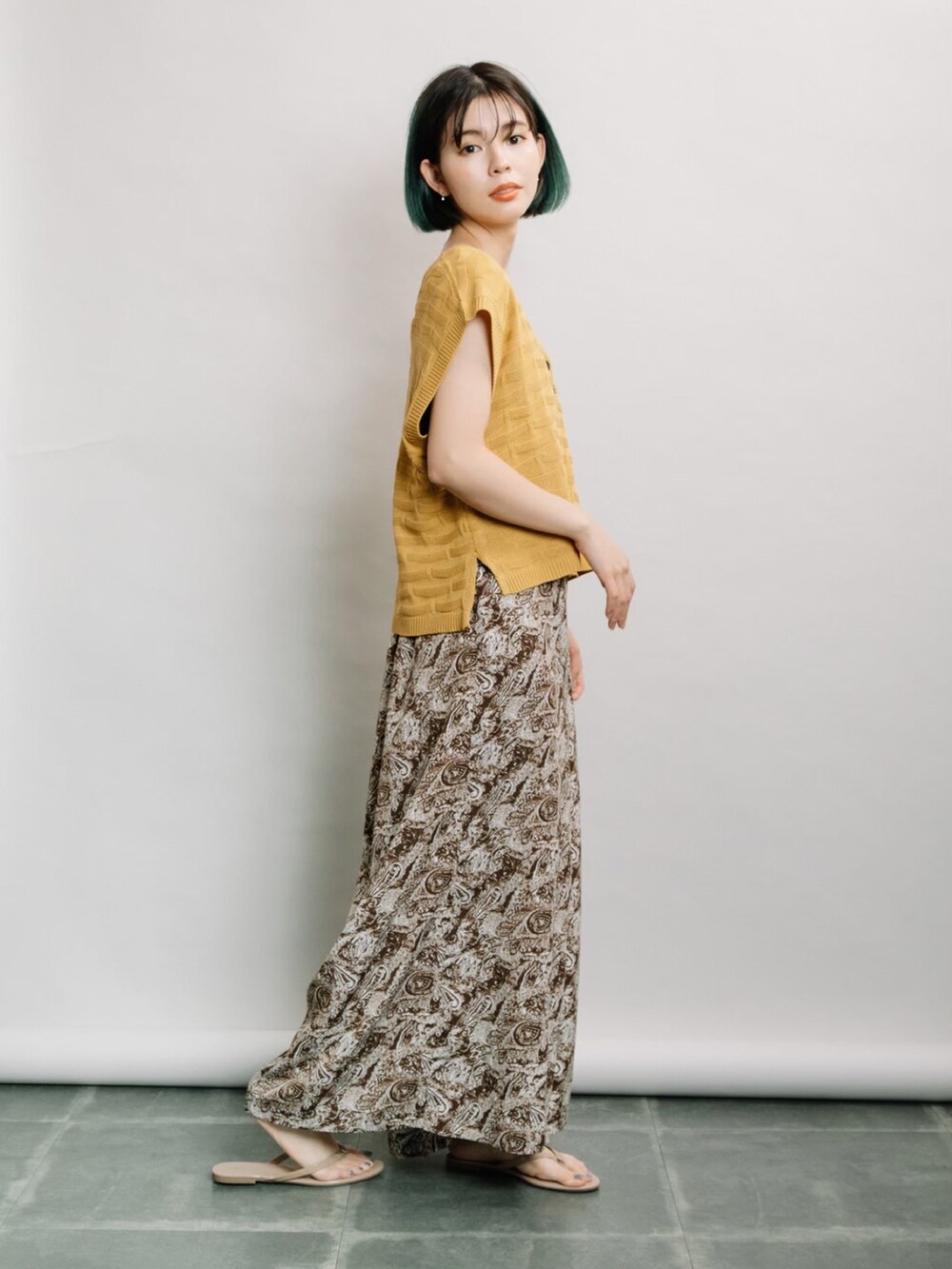 イエロー系のベスト、ブラウン系のその他パンツ、ブラック系のタンクトップを着用したレディースの春コーディネートの2枚目の写真