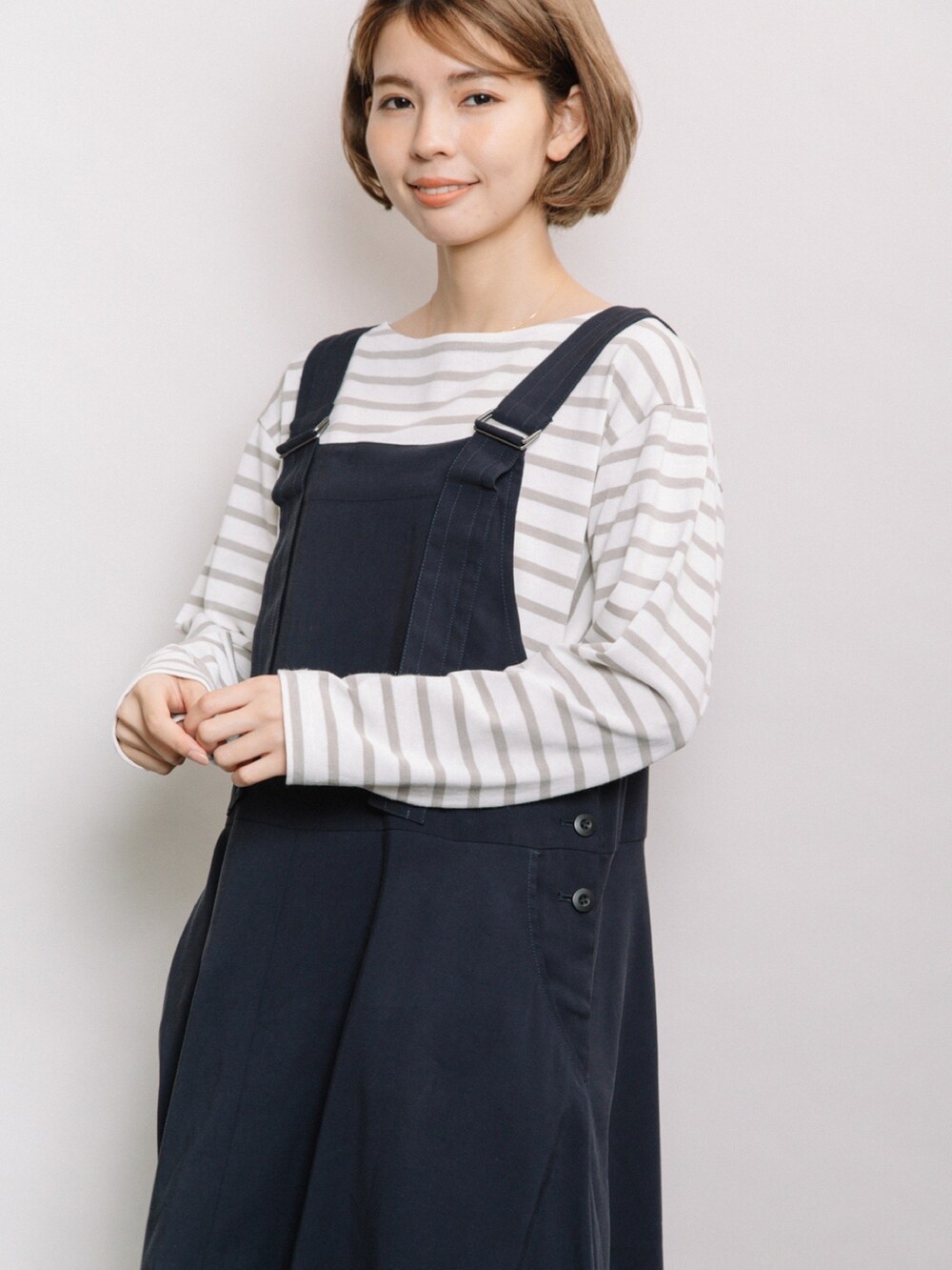 ブルー系のジャンパースカート、ベージュ系のニット/セーターを着用したレディースの冬コーディネートの4枚目の写真