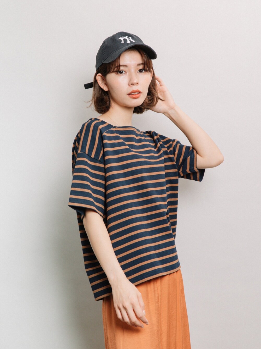 ブルー系のTシャツ/カットソー、オレンジ系のスカート、ブルー系のキャップを着用したレディースの夏コーディネートの2枚目の写真