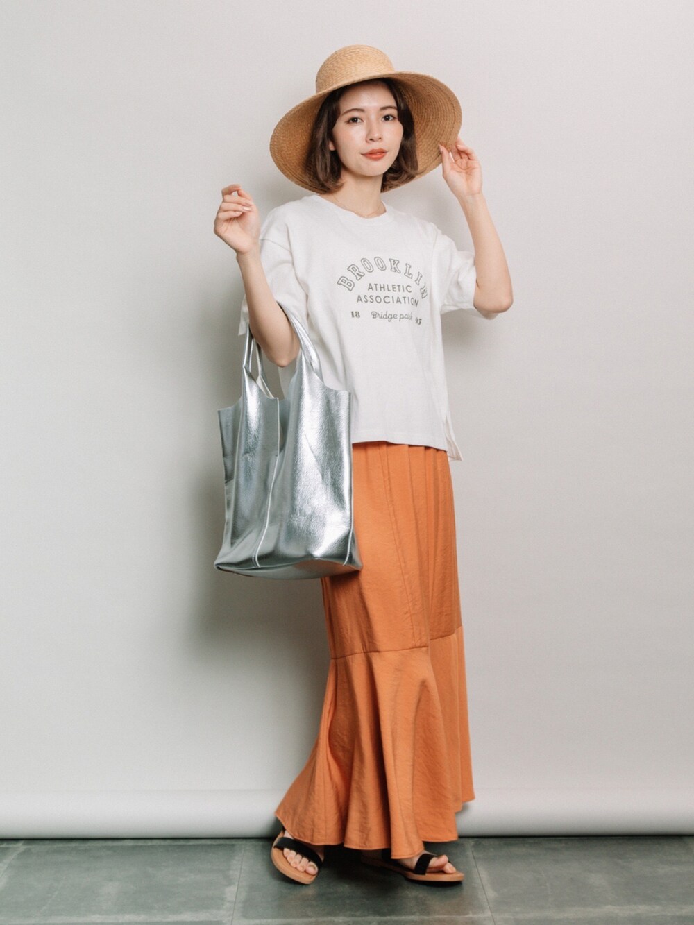 ホワイト系のTシャツ/カットソー、オレンジ系のスカート、ベージュ系のハットを着用したレディースの夏コーディネートの2枚目の写真