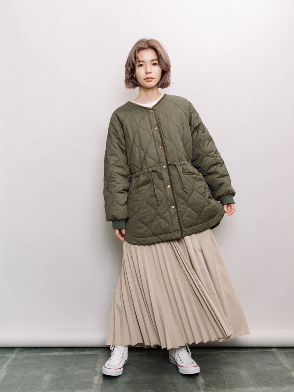 グリーン系のその他アウター、ベージュ系のスカート、ホワイト系のスニーカーを着用したレディースの冬コーディネートの3枚目の写真