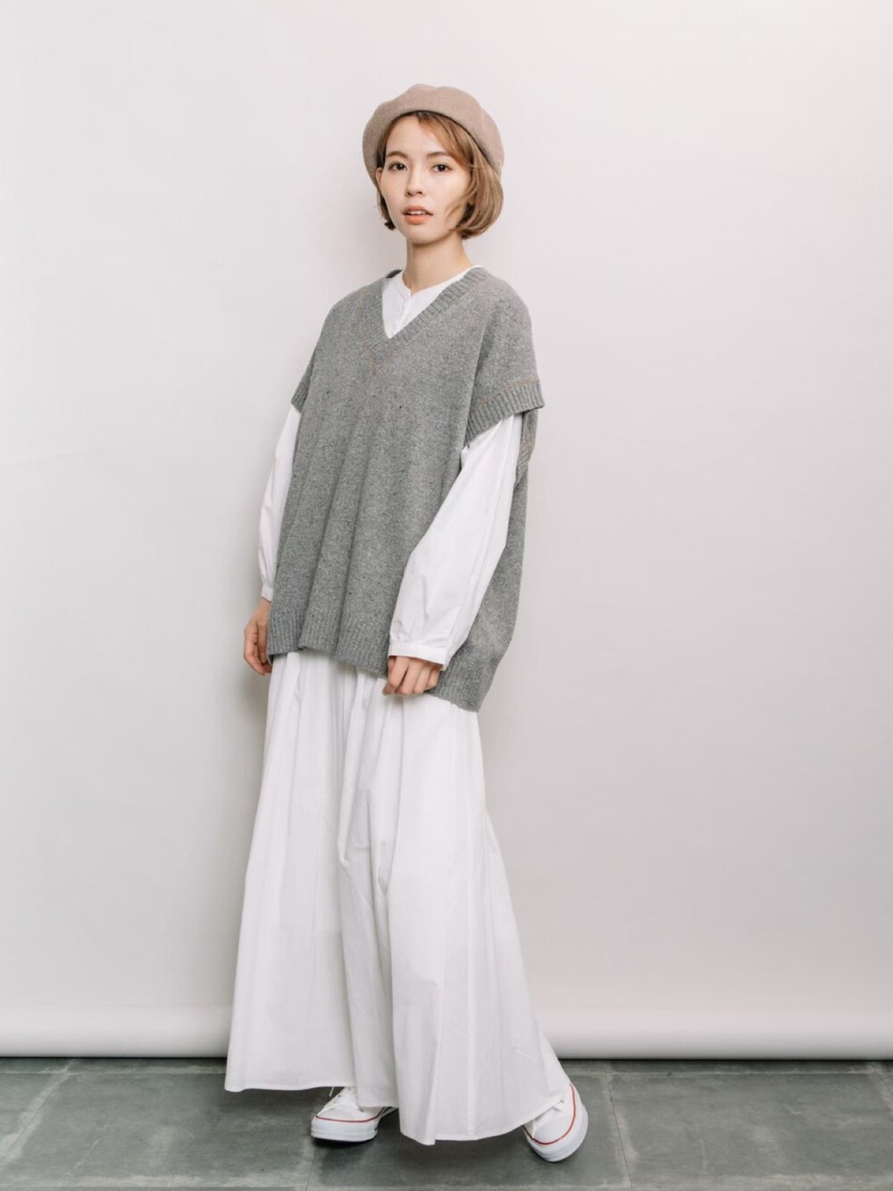 グレー系のベスト、ホワイト系のシャツ/ブラウス、ホワイト系のスカートを着用したレディースの冬コーディネートの2枚目の写真