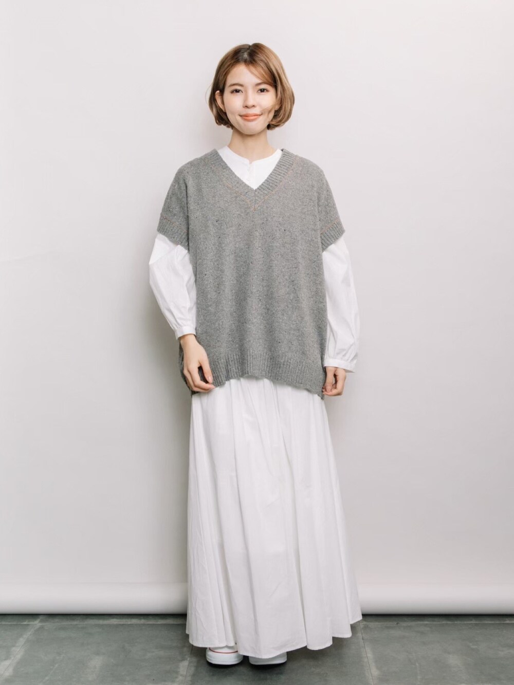 グレー系のベスト、ホワイト系のシャツ/ブラウス、ホワイト系のスカートを着用したレディースの春コーディネートの3枚目の写真
