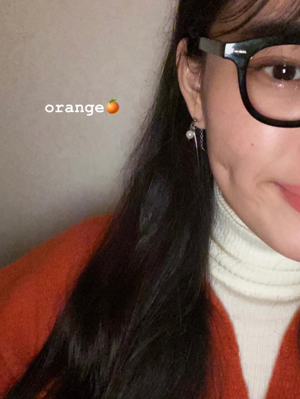 ブルー系のデニムパンツ、オレンジ系のニット/セーター、ホワイト系のニット/セーターを着用したレディースの冬コーディネートの3枚目の写真