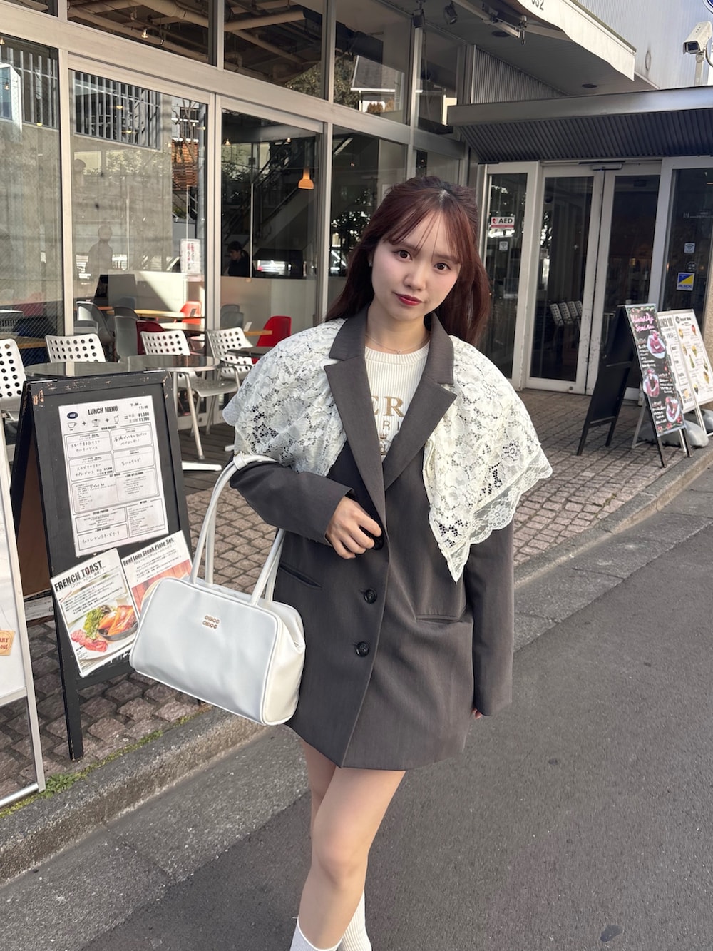 グレー系のテーラードジャケット、ホワイト系のボストンバッグ、ホワイト系のニット/セーターを着用したレディースの冬コーディネートの2枚目の写真