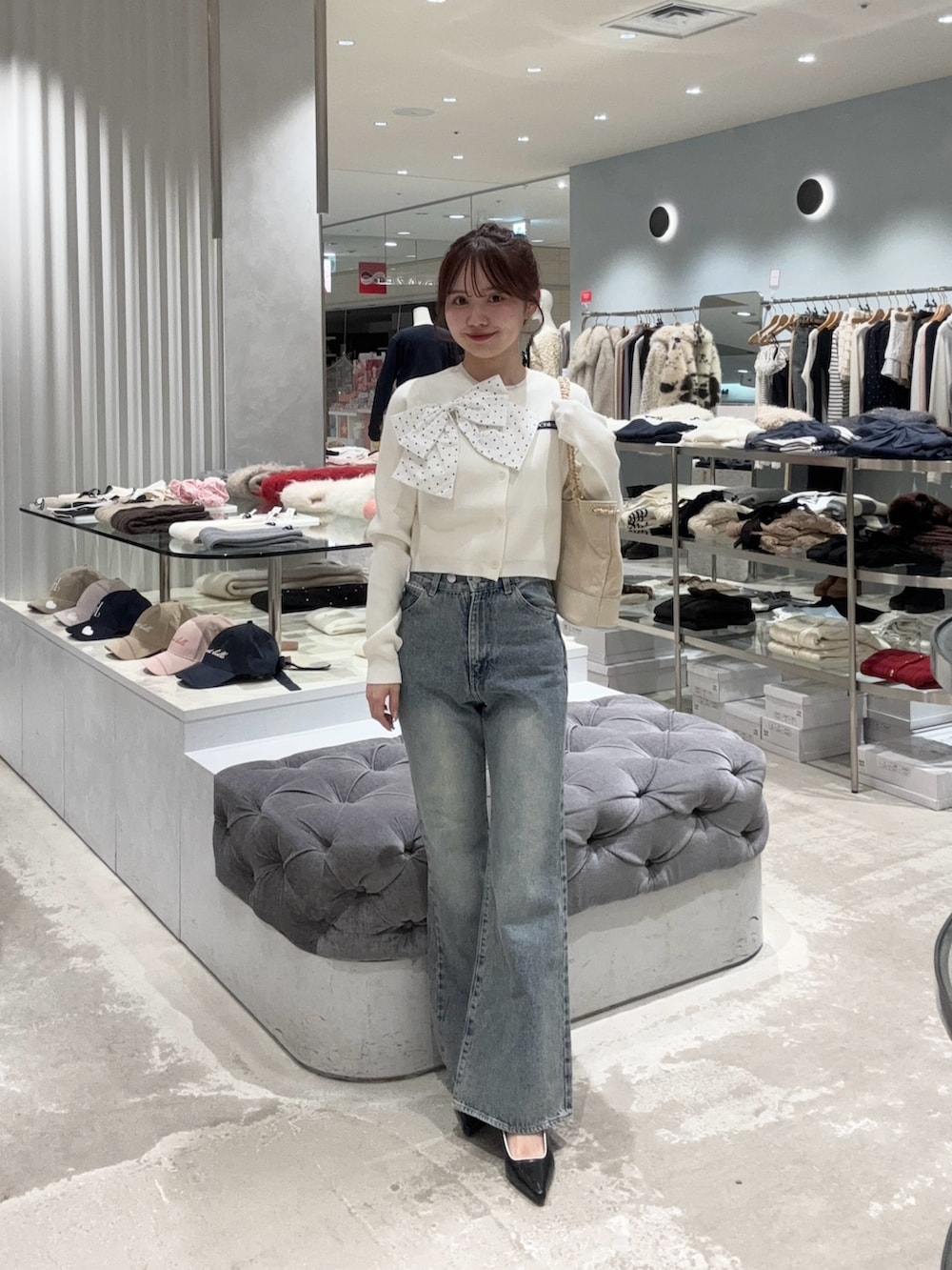 ホワイト系のカーディガン/ボレロ、ブルー系のデニムパンツ、ホワイト系のショルダーバッグを着用したレディースの冬コーディネートの3枚目の写真