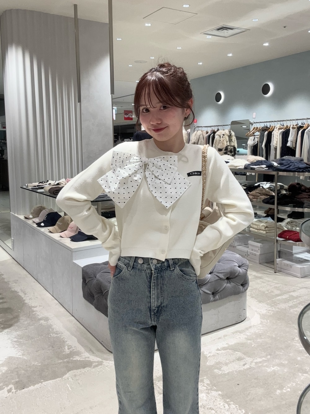 ホワイト系のカーディガン/ボレロ、ブルー系のデニムパンツ、ホワイト系のショルダーバッグを着用したレディースの冬コーディネートの2枚目の写真