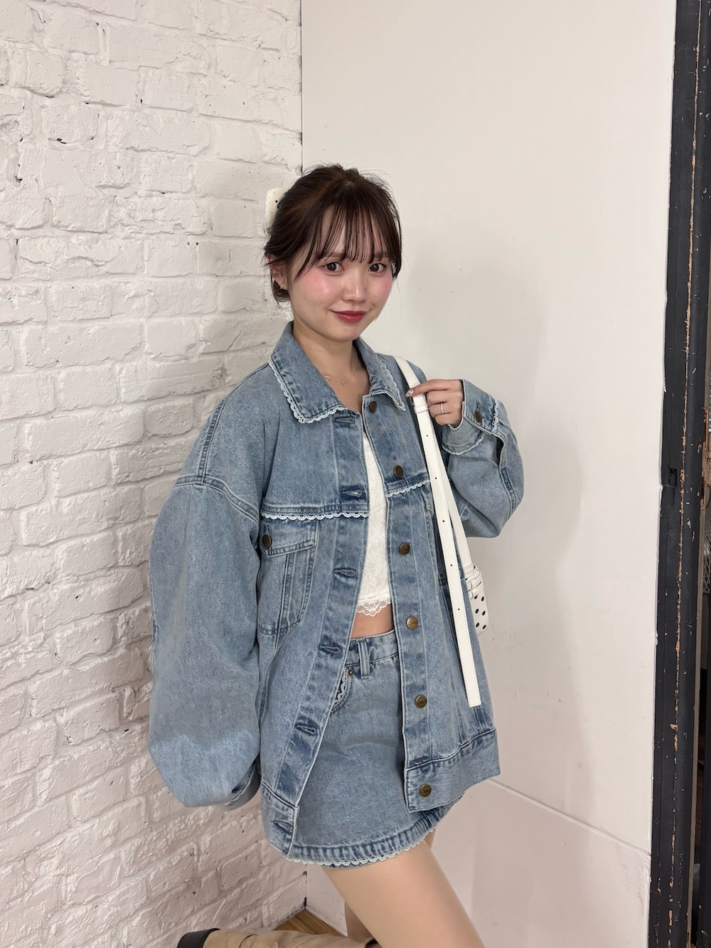 ブルー系のデニムジャケット、ブルー系のスカート、ホワイト系のキャミソールを着用したレディースの春コーディネートの2枚目の写真