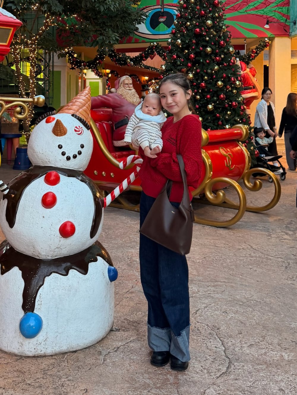 ブラウン系のショルダーバッグ、ブラック系のブーツ、レッド系のニット/セーターを着用したレディースの春コーディネートの3枚目の写真