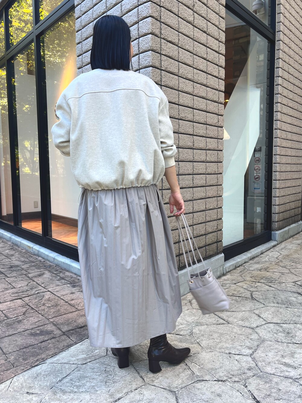 ベージュ系のブルゾン、ベージュ系のワンピース、グレー系のトートバッグを着用したレディースの秋コーディネートの2枚目の写真