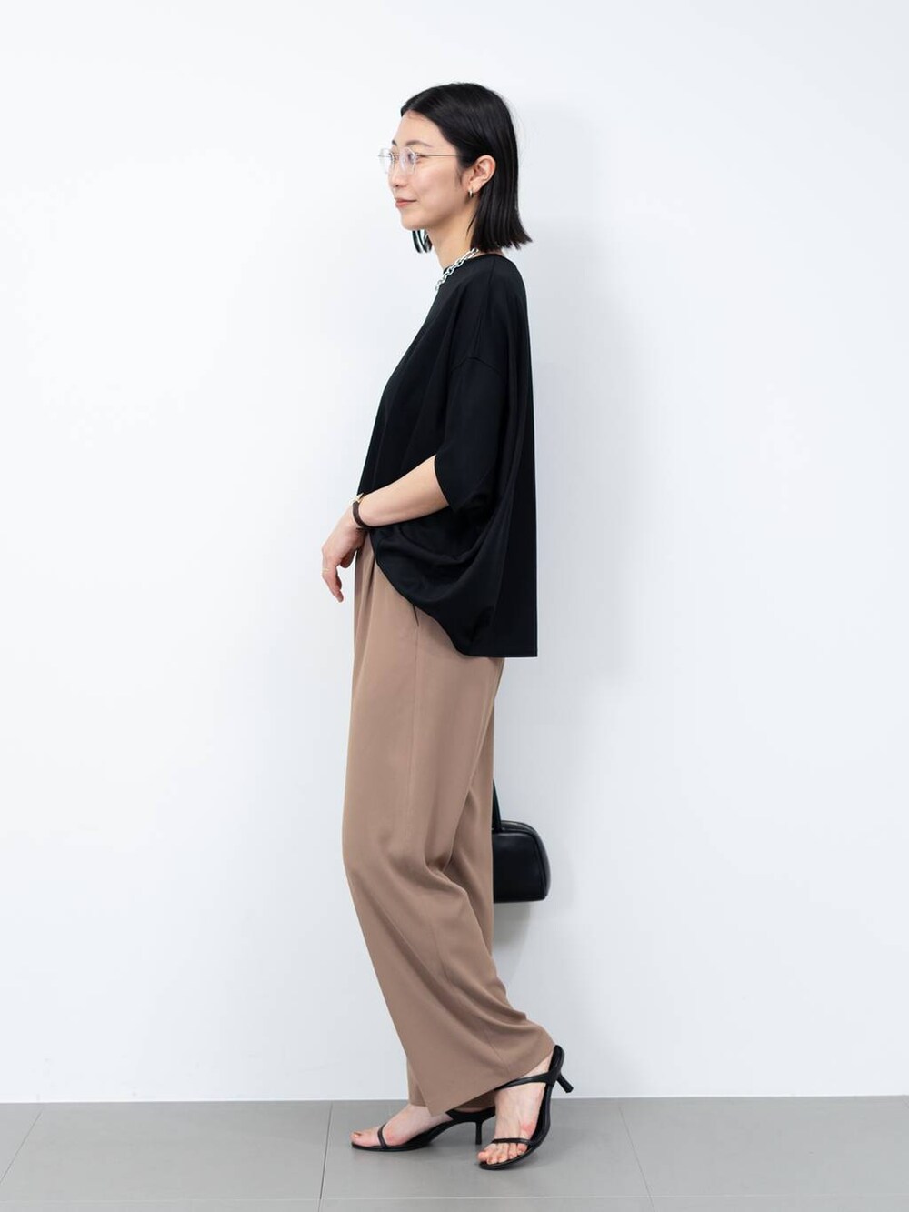 ブラック系のボストンバッグ、ブラウン系のスラックス、ブラック系のサンダルを着用したレディースの春コーディネートの2枚目の写真