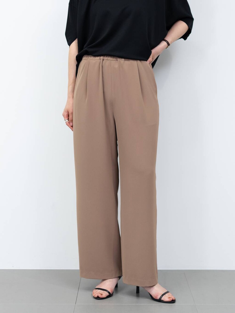 ブラック系のボストンバッグ、ブラウン系のスラックス、ブラック系のサンダルを着用したレディースの春コーディネートの3枚目の写真