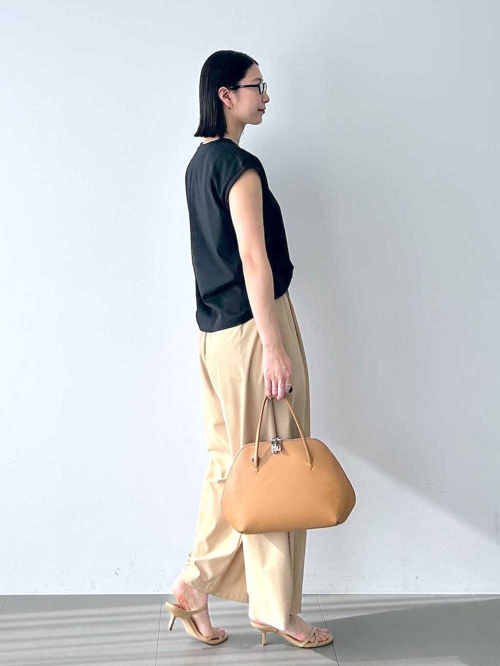 ブラック系のTシャツ/カットソー、ブラウン系のトートバッグ、ベージュ系のその他パンツを着用したレディースの春コーディネートの4枚目の写真