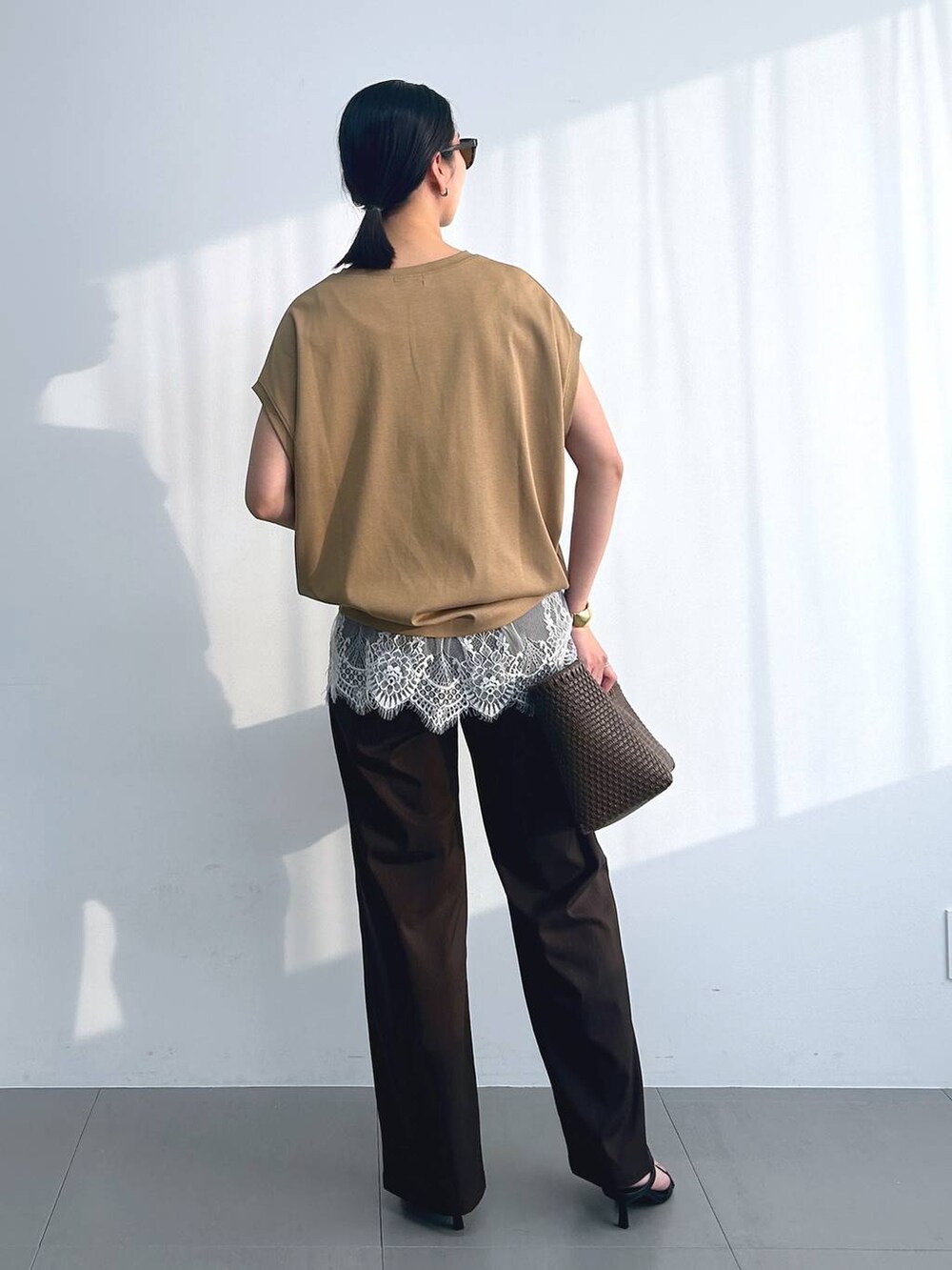 ブラウン系のチノパンツ、ホワイト系のキャミソール、ブラック系のサンダルを着用したレディースの春コーディネートの4枚目の写真