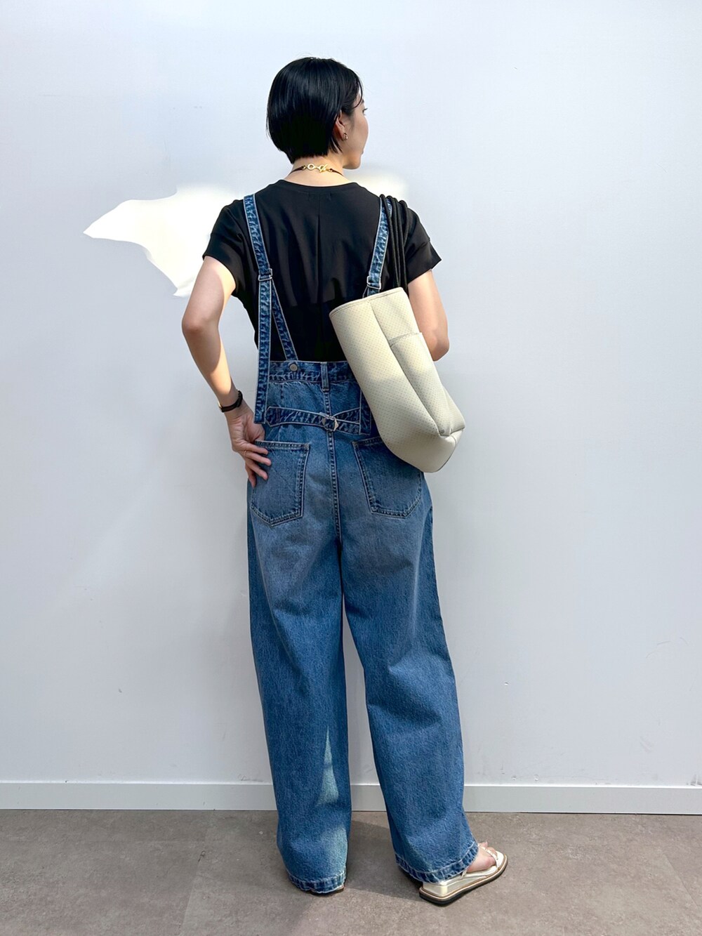ブラック系のTシャツ/カットソー、ブルー系のデニムパンツ、ベージュ系のトートバッグを着用したレディースの春コーディネートの3枚目の写真